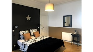 Un dormitorio con cama, una decoración con motivos de estrellas, una mesita de noche, una lámpara y un radiador.