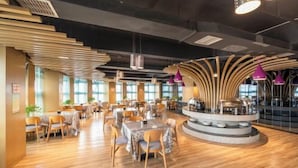 Un restaurante moderno con suelo de madera, mesas redondas e iluminación colgante morada.