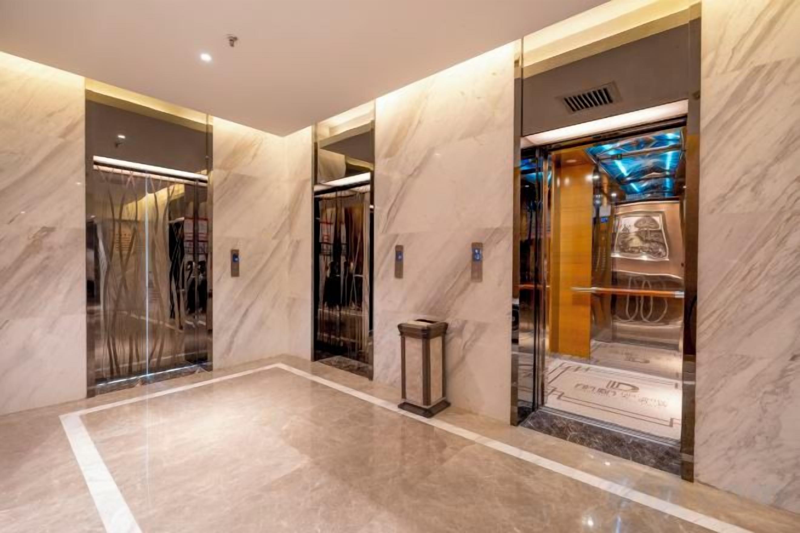 Interior moderno de ascensor con paredes de mármol y detalles metálicos.