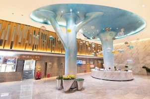 Un vestíbulo moderno con una estructura en forma de árbol, una recepción y un suelo de mármol.