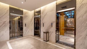 Un ascensor moderno con interior metálico y suelo de mármol.