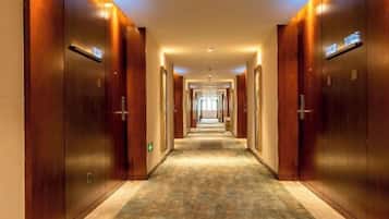 A long, narrow hotel corridor with wooden doors on either side and a carpeted floor.