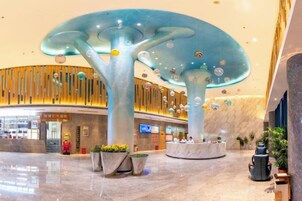 Un vestíbulo espacioso con una estructura singular semejante a un árbol, zonas de estar y un diseño moderno.