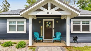 A house with a porch, two Adirondack chairs, a welcome sign, and a number 4646 on the front. - Greenbriar Getaway: Quaint Cottage in Canandaigua (Canandaigua)
