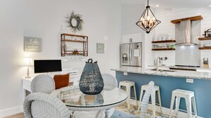 A modern kitchen with white cabinetry, a stainless steel refrigerator, and a blue accent wall. - Greenbriar Getaway: Quaint Cottage in Canandaigua (Canandaigua)