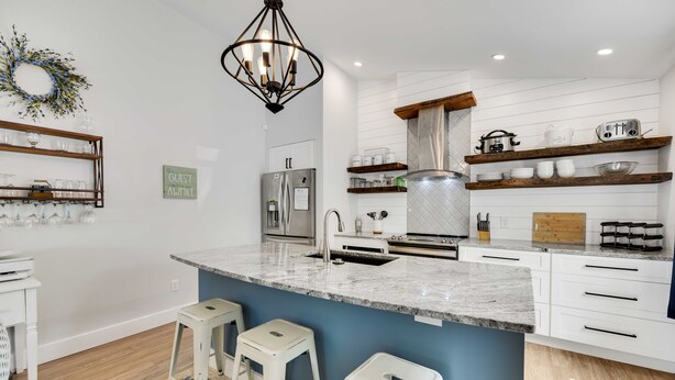 A modern kitchen with a central island, stainless steel appliances, and wooden shelves. - Greenbriar Getaway: Quaint Cottage in Canandaigua (Canandaigua)
