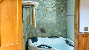 Een badkamer met een stenen muur, houten balken, een bad en een handdoekrek.