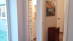 A bedroom with a bed, a bathroom with a shower curtain, a wooden dresser, and a painting on the wall. - Cappucci Garden House, nice apartment with little garden few steps from seafront (Pozzuoli)