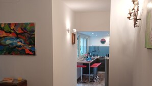 A living room with a green sofa, a wooden cabinet, and a colorful abstract painting on the wall. - Cappucci Garden House, nice apartment with little garden few steps from seafront (Pozzuoli)