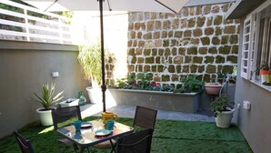 A patio with a table and chairs, surrounded by potted plants and a stone wall. - Cappucci Garden House, nice apartment with little garden few steps from seafront (Pozzuoli)