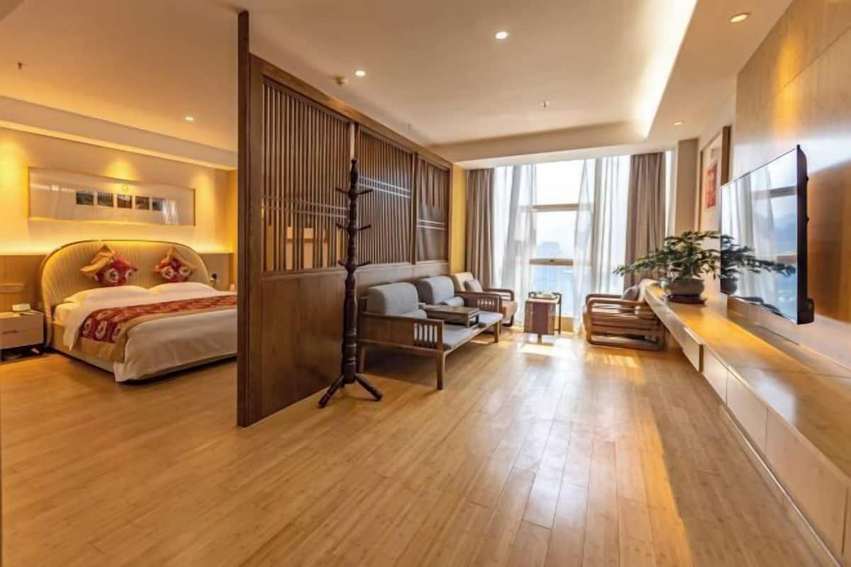 Une chambre d’hôtel moderne équipée d’un lit, d’un canapé, d’une télévision et d’une grande fenêtre.