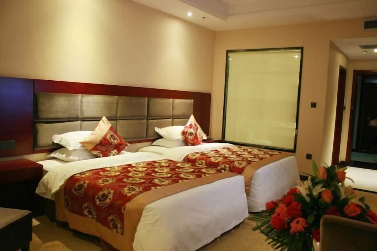 Une chambre d’hôtel avec un grand lit, deux tables de chevet et une grande fenêtre.