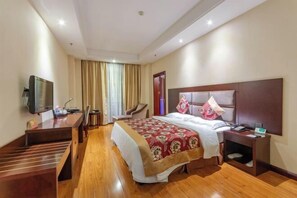 Ein Hotelzimmer mit einem Bett, einem Schreibtisch, einem Stuhl, einem Fernseher und einem Kleiderschrank.