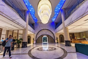 A spacious lobby with a central circular design, a reception desk, and a modern chandelier.