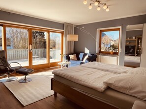 A bedroom with a large bed, a chair, a small table, and a view of the outdoors through a sliding door. - A whole house just for you (Haundorf)