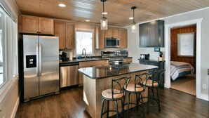 Una cocina moderna con armarios de madera, electrodomésticos de acero inoxidable y una isla central con taburetes de bar.