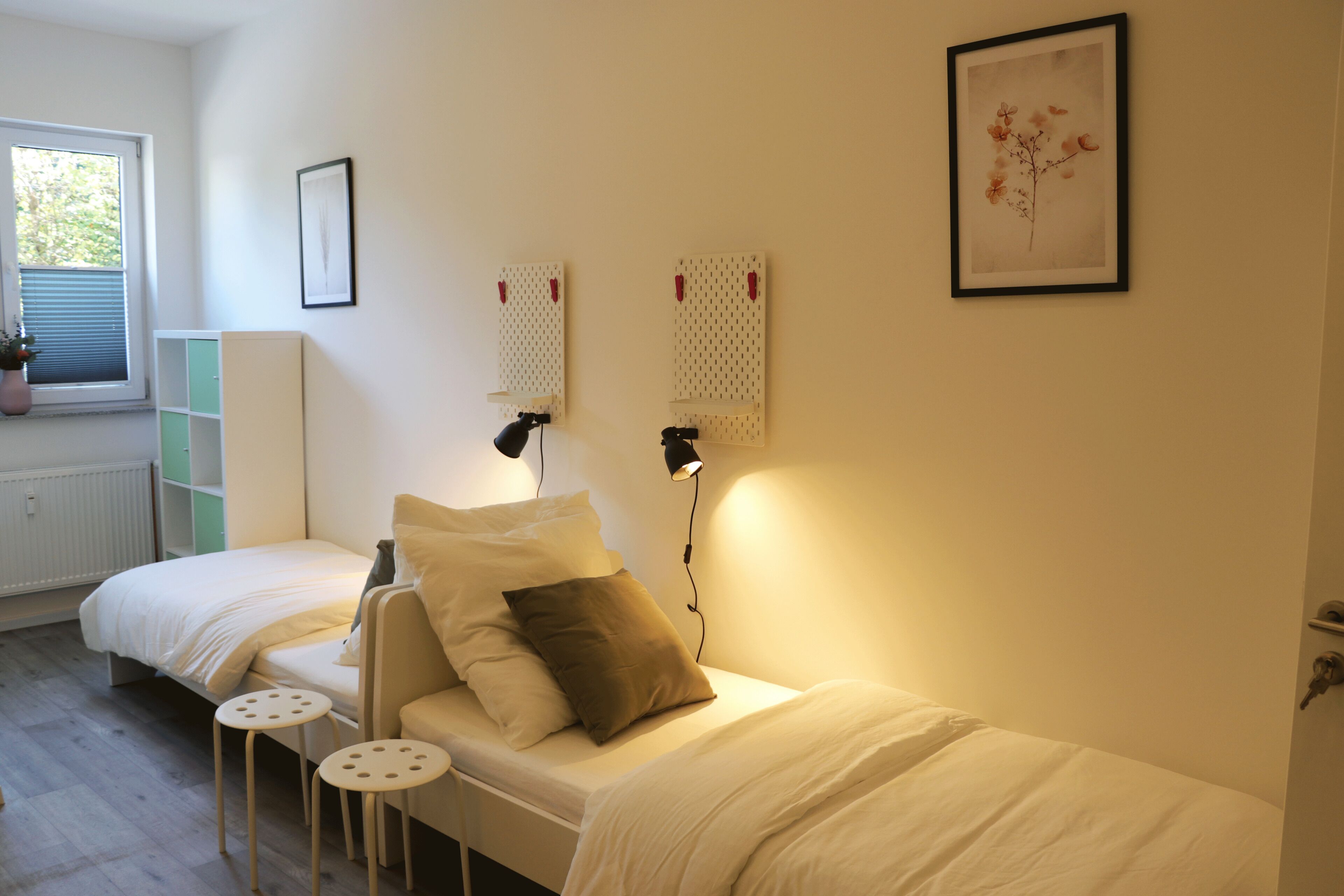 A bedroom with a bed, two bedside tables, a window, and a radiator.