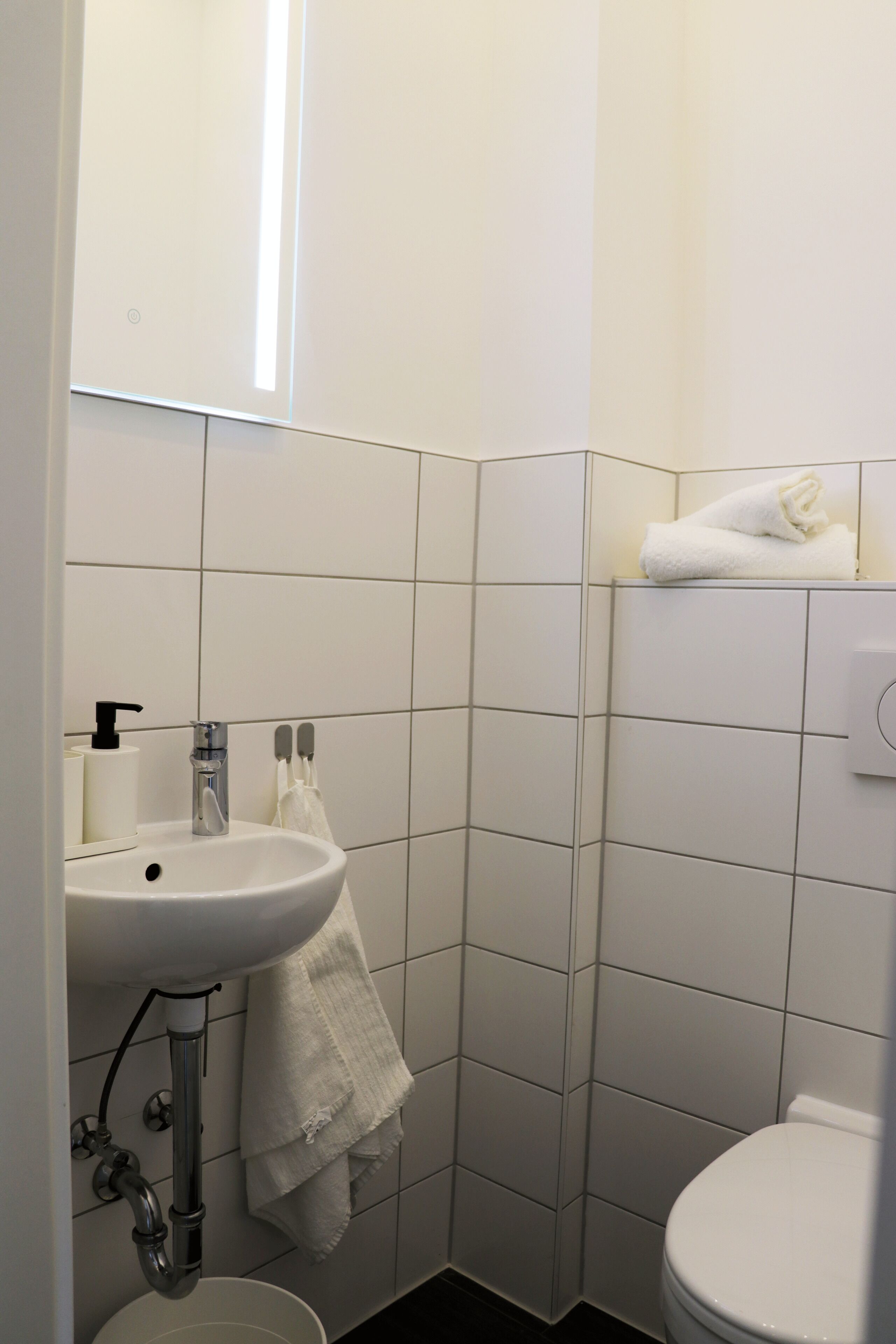 Un bagno con lavandino, specchio e servizi igienici bianchi.