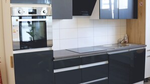 Una cocina moderna con armarios negros, un horno de acero inoxidable y un mueble de madera.