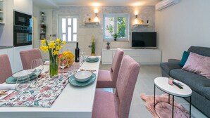 A modern living space with a dining area, kitchen, and seating area. - Apartment Papilio (Brela)