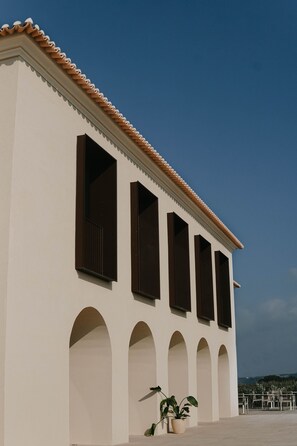 Un bâtiment à la façade blanche, doté de nombreuses fenêtres et d’un toit recouvert de tuiles.