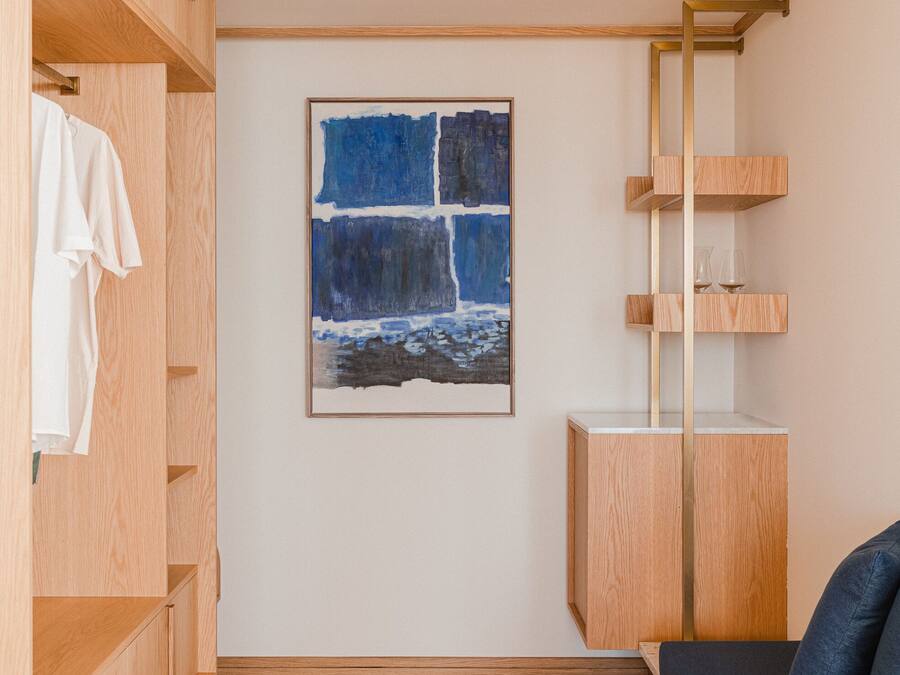 Una habitación con un armario de madera, un cuadro enmarcado, un mueble de madera y un sofá azul.