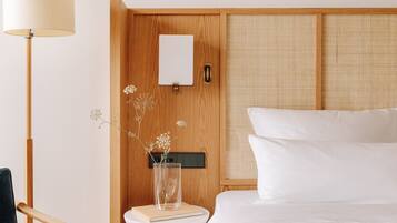 A bedroom with a bed, bedside table, lamp, chair, and a wooden wardrobe.
