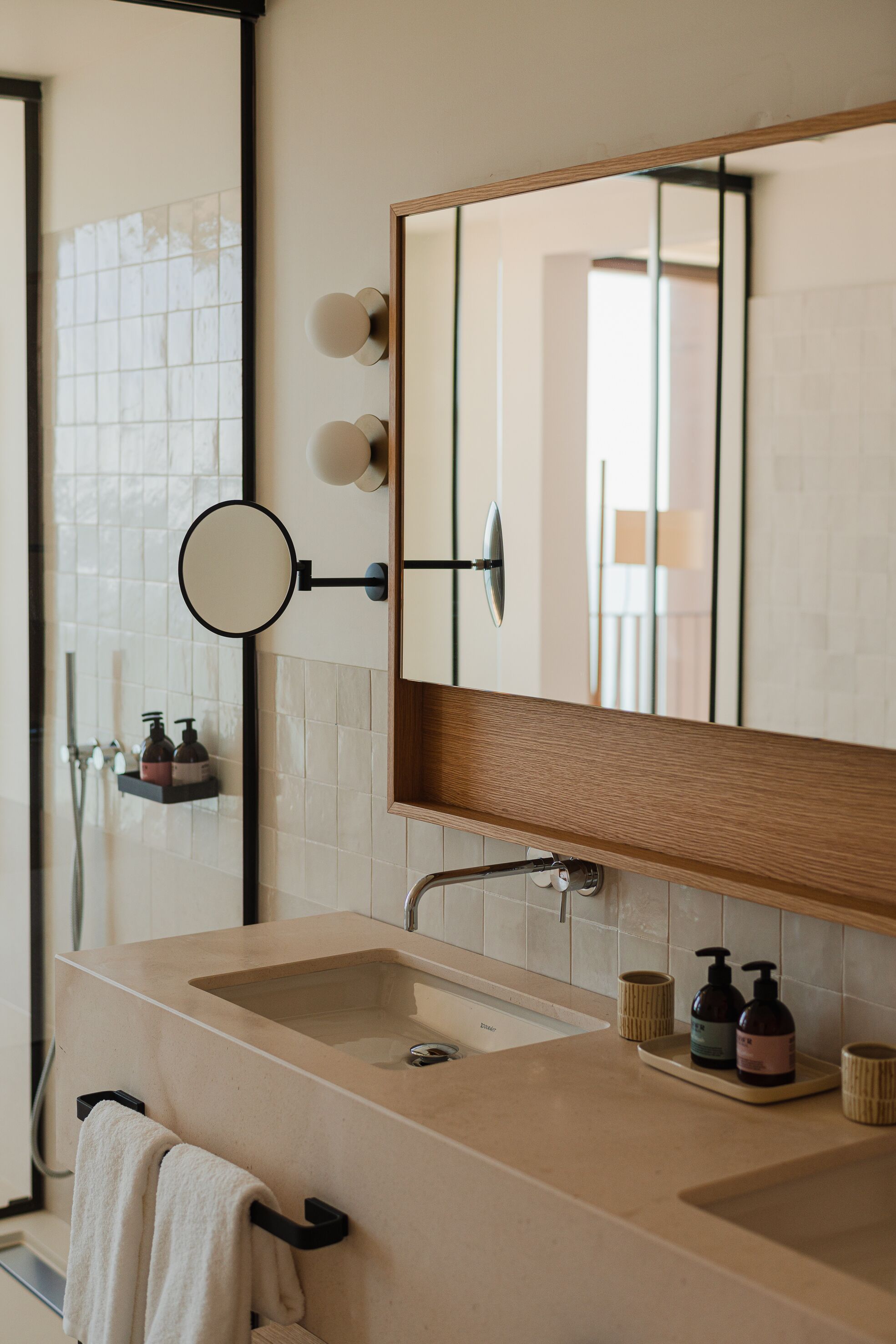 A bathroom with a beige sink, a mirror, and a towel rack.