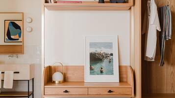 Quarto moderno com cama de madeira, mesa de cabeceira com abajur, quadro emoldurado e guarda-roupa.