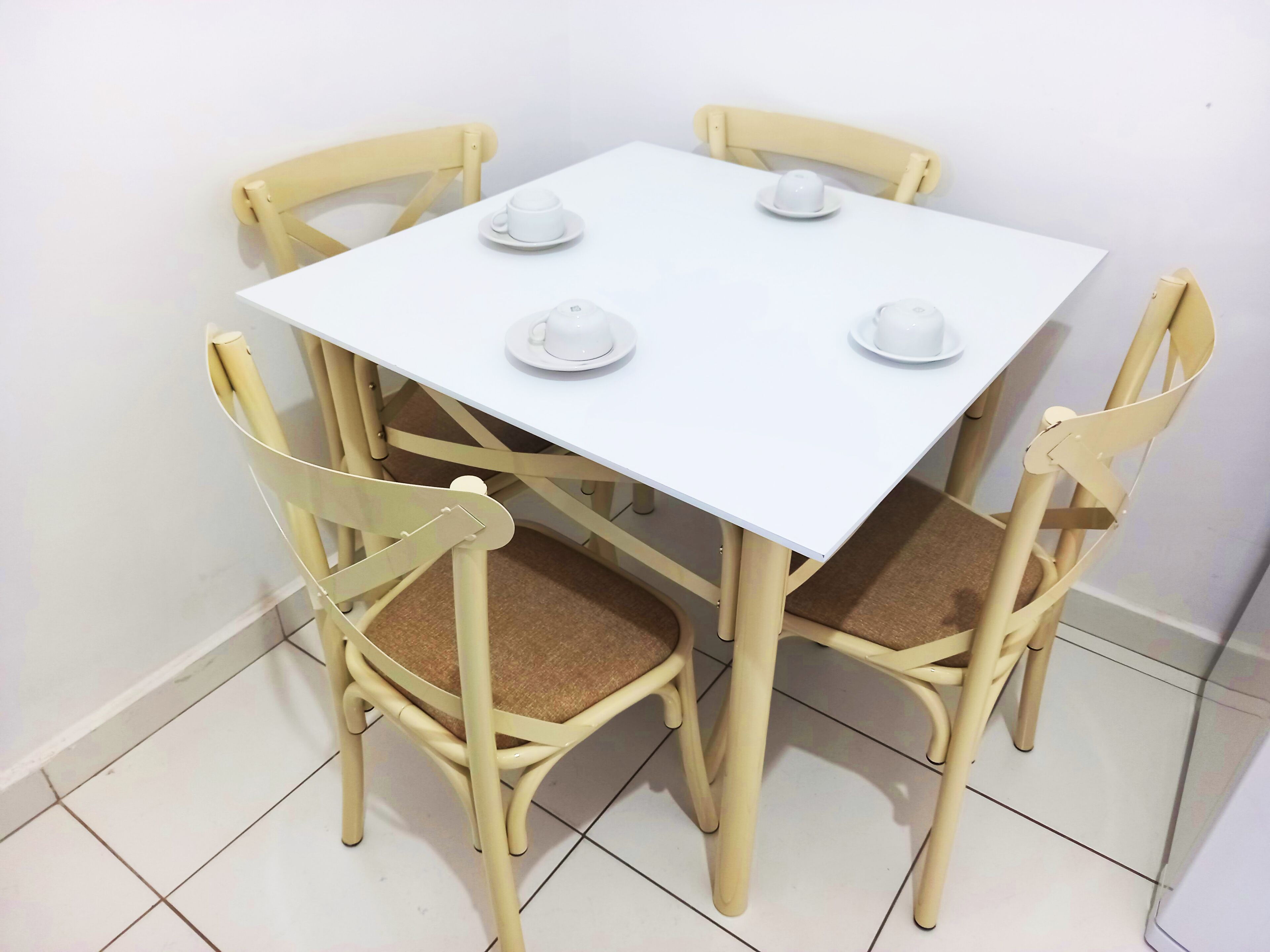 Une table carrée blanche, accompagnée de quatre chaises, chacune dotée d’un coussin.