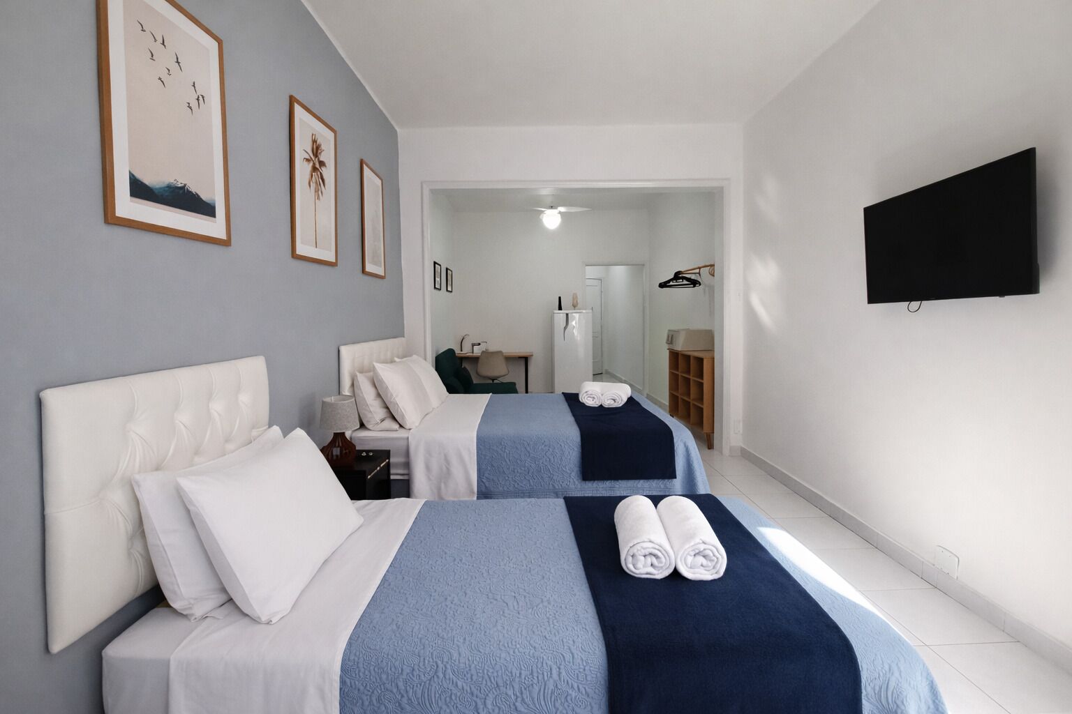 A hotel room with two beds, a flat-screen TV, and a desk with a chair.