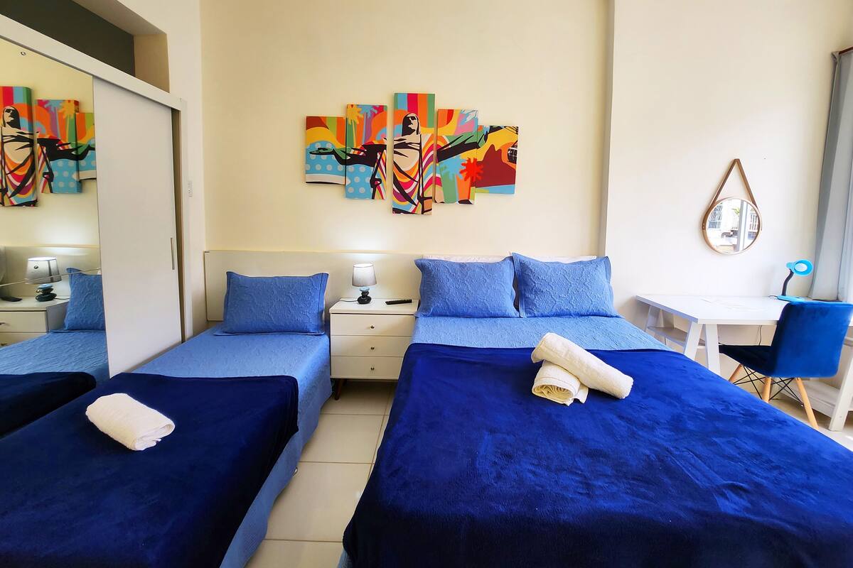 Una habitación de hotel con dos camas, un escritorio, una silla y un espejo.