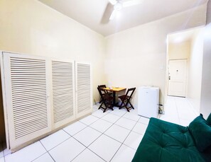A compact living space with a dining area, a small refrigerator, and a green sofa. - Copacabana Best Spot (Rio de Janeiro)