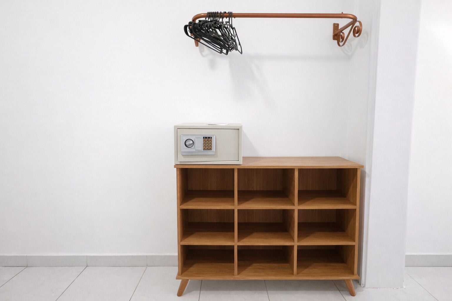 Una estantería de madera con una radio, un colgador de metal con asa curva y una pared blanca.