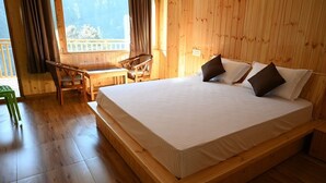 Ein Zimmer mit Holzboden, einem Bett, einem Sessel und einem kleinen Tisch.