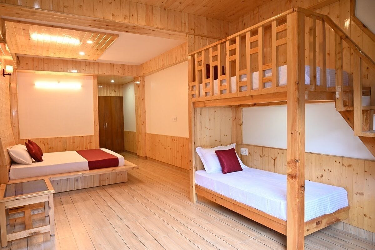 A wooden cabin with two bunk beds, a small table, and a staircase.