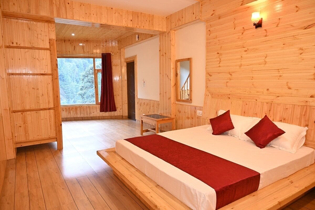 A wooden-paneled bedroom with a large bed, a small table, and a window with a view of trees.