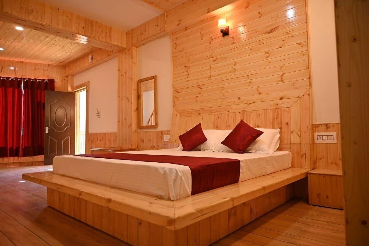 A wooden-paneled bedroom with a bed, red curtains, and a wooden bench.