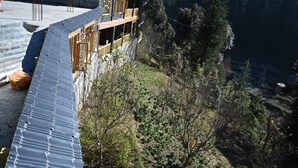 Ein Gebäude mit geneigtem Dach, Holzbalkonen und Blick auf ein bewaldetes Tal.