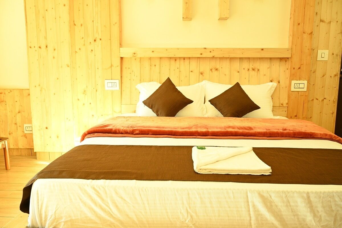 Una habitación con paneles de madera, una cama, dos almohadas, una toalla doblada y una mesita de noche.