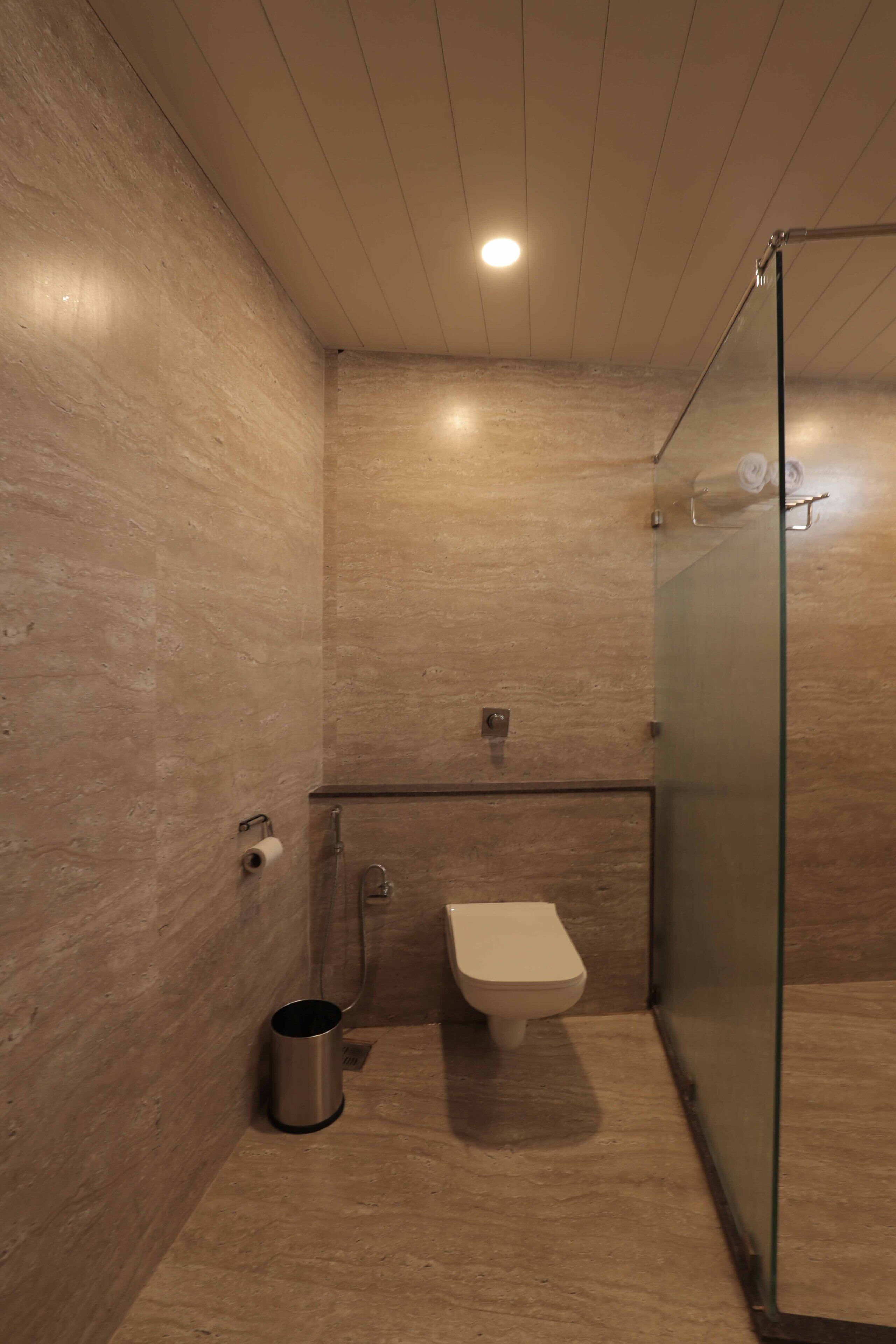 Un baño moderno con cabina de ducha de vidrio, inodoro y cubo de basura.