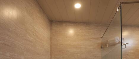 Un baño moderno con cabina de ducha de vidrio, inodoro y cubo de basura.