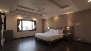 Una camera da letto moderna con un letto grande, una ventola a soffitto, illuminazione a incasso e una finestra con tende.