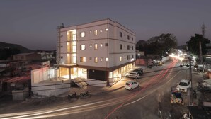 Un edificio a più piani con tetto piatto, diverse finestre e una scala che conduce all'ingresso.