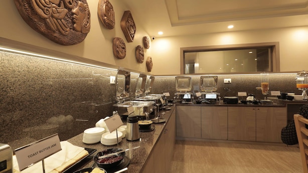 Un'impostazione per buffet con diverse postazioni gastronomiche, tra cui una sezione con pane tostato, burro e marmellata, e decorazioni artistiche alle pareti.
