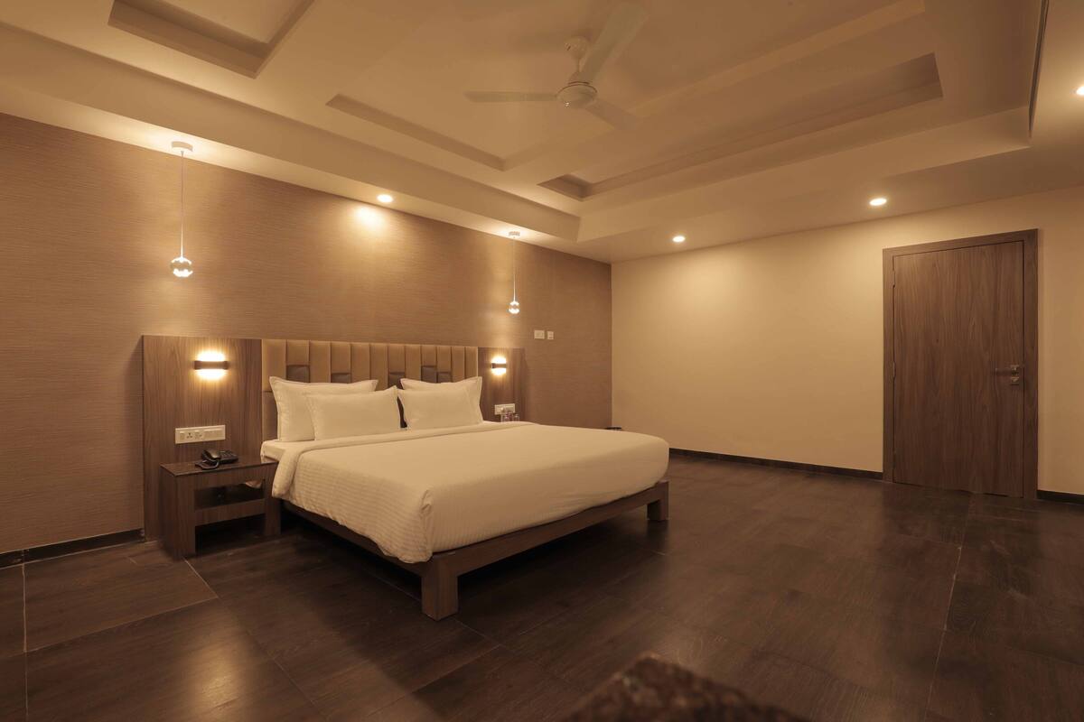 A modern bedroom with a large bed, wooden headboard, bedside lamps, and a ceiling fan.