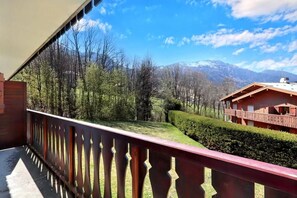 Un balcon donnant sur un paysage montagneux, une clôture en bois et un bâtiment avec un toit rouge.