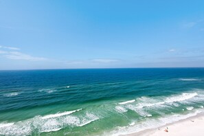 A beach with clear blue water and a sandy shore.