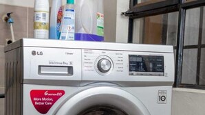 A front-loading LG Direct Drive 8kg washing machine with a digital display, a red sticker, and detergent bottles on top. - Stay.Plus Ruaka View Apartment (Ruaka)