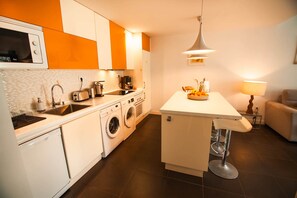 Eine moderne Küche mit einer zentralen Kochinsel, integrierten Geräten und einer Sitzecke mit einer Lampe.